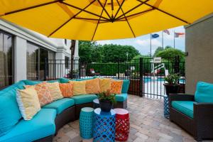a patio with a blue couch and a yellow umbrella at Hampton Inn Winston-Salem Hanes Mall in Winston-Salem