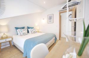 a white bedroom with a bed and a table at Kasa 23 Cascais in Cascais