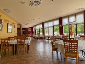 un restaurante con mesas y sillas blancas y ventanas en Prado de las merinas, en Caleruega