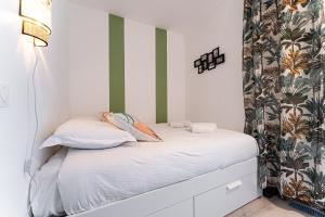 a small bedroom with a bed with white sheets and pillows at Piton des Neiges - Nid douillet terrasse vue port in Arcachon
