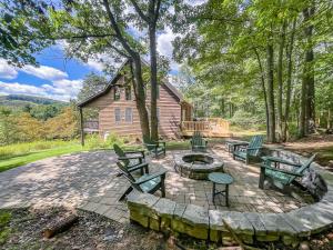 a patio with benches and a fire pit in front of a house at Modern Cabin with Hot Tub and Fire Pit in Swanton