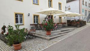 un patio al aire libre con mesas, sillas y sombrillas en Gasthof zum Lehnerwirt, en Breitenbrunn