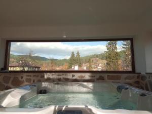 a bath tub in a room with a large window at Villa Lyutovi Holiday Home in Koprivshtitsa