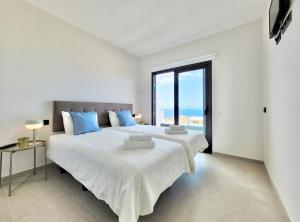 a white bedroom with a large bed with a large window at Mar Azul in Puerto de la Cruz