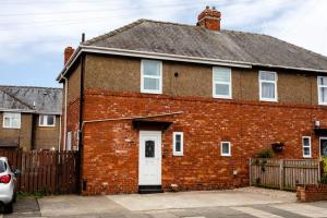 a red brick house with a white door at Plessey House Blyth by #ShortStaysAway in Cowpen