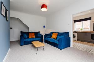 Plessey House Blyth by #ShortStaysAway في Cowpen: غرفة معيشة مع كنبتين زرقاوين وطاولة