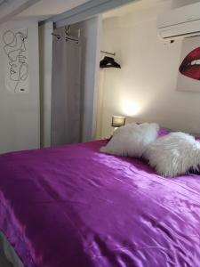 a purple bed with two white pillows on it at CHARMANTE VILLA HELIOVILLAGE CAMP NATURISTE in Cap d'Agde