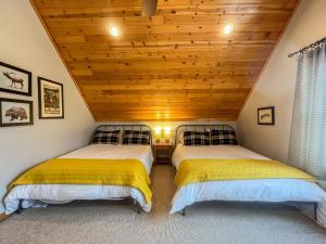 two beds in a room with a wooden ceiling at Modern Cabin with Hot Tub and Fire Pit in Swanton