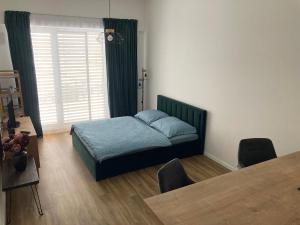 1 dormitorio con cama, mesa y ventana en Moderný apartmán A408 v centre NR, parkovanie v cene, en Nitra
