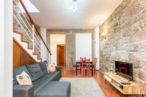 a living room with a couch and a stone wall at Casa da Sé Historic next to Braga Cathedral by Sé Apartamentos in Braga