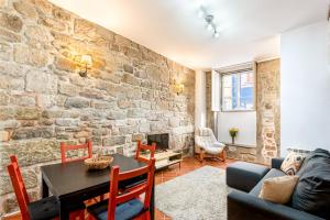 a living room with a table and a stone wall at Casa da Sé Historic next to Braga Cathedral by Sé Apartamentos in Braga +7 photos