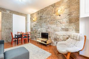 a living room with a stone wall at Casa da Sé Historic next to Braga Cathedral by Sé Apartamentos in Braga