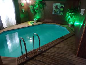 una piscina alargada con suelo de madera y luces verdes en Manoir Saint Martin, en Percy