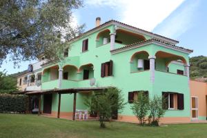 a large green building with windows and a yard at Affittacamere La Petra Longa in San Teodoro