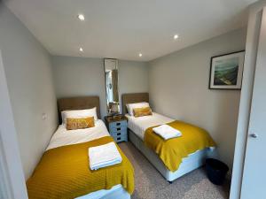two beds in a small room with yellow blankets at Tanyard Barn - North Yorkshire in York