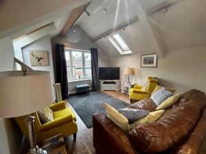 a living room with a brown leather couch and yellow chairs at Tanyard Barn - North Yorkshire in York