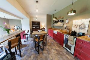 a kitchen with red cabinets and a wooden table at Railway Cottage in Killin
