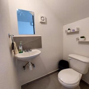 y baño con aseo, lavabo y espejo. en Casa Paraíso - Brandeburgo, en Veracruz