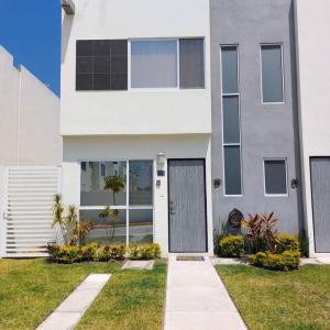 uma casa branca com uma porta num quintal em Casa Paraíso - Brandeburgo em Veracruz
