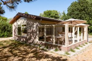 a small house with a patio and an umbrella at Mamooi Julianadorp in Julianadorp