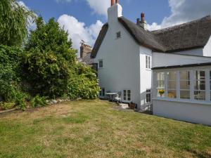 a white house with a yard in front of it at Thatched Cottage in Bridport
