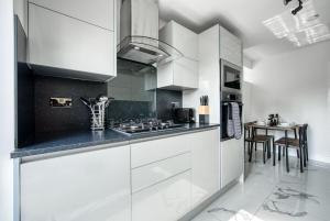 a white kitchen with white cabinets and a table at Aryas Homes Oxford - Headington in Oxford