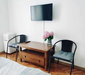 einen Schreibtisch mit einer Vase aus Blumen und 2 Stühlen in der Unterkunft Apartman Marija in Poreč