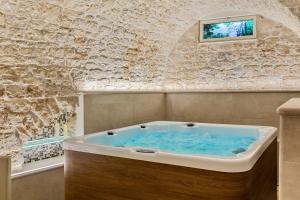 a bath tub in a room with a stone wall at Casa Massima Suites & SPA in Casamassima
