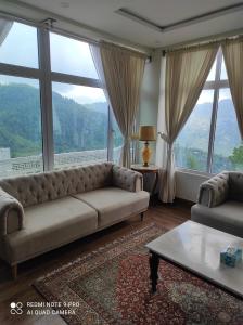 a living room with a couch and large windows at Himalaya Villas in Murree