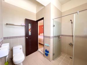 a bathroom with a toilet and a glass shower at Brother Homestay in Taitung City