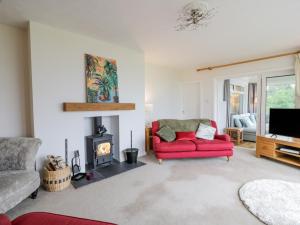 a living room with a red couch and a fireplace at Knockendoch in Dumfries