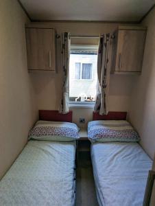 a small room with two beds and a window at Littlesea Caravan on a Fabulous elevated position Haven Weymouth in Weymouth