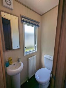 a bathroom with a toilet and a sink and a window at Littlesea Caravan on a Fabulous elevated position Haven Weymouth in Weymouth