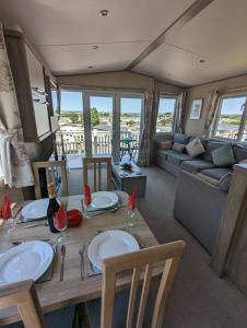 sala de estar con mesa y sofá en Littlesea Caravan on a Fabulous elevated position Haven Weymouth, en Weymouth