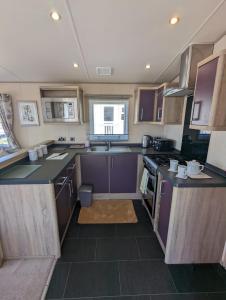 a small kitchen with purple cabinets and a stove at Littlesea Caravan on a Fabulous elevated position Haven Weymouth in Weymouth