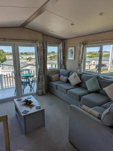 a living room with couches and a table and windows at Littlesea Caravan on a Fabulous elevated position Haven Weymouth in Weymouth