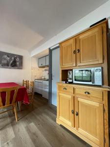 a kitchen with wooden cabinets with a microwave and a table at Appartement pied des pistes Champagny-en-Vanoise in Champagny-en-Vanoise