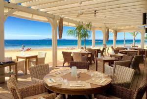 een restaurant op het strand met tafels en stoelen bij Petit coin de paradis les pieds dans l’eau in La Londe-les-Maures