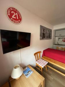 a room with a red bed and a table and a television at Appartement pied des pistes Champagny-en-Vanoise in Champagny-en-Vanoise