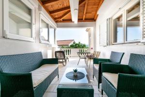 a patio with green chairs and a table at Apartments Miranda in Lopar