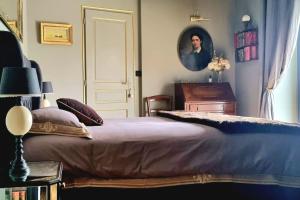 um quarto com uma cama e um retrato de um homem em À Saint-Pair-sur-Mer -Maison de vacances- Double Perspective - Manche em Saint-Pair-sur-Mer