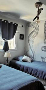 um quarto com 2 camas e um mural de cavalo marinho na parede em À Saint-Pair-sur-Mer -Maison de vacances- Double Perspective - Manche em Saint-Pair-sur-Mer