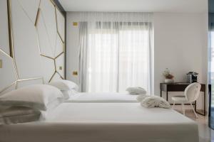 2 Betten in einem weißen Schlafzimmer mit Fenster in der Unterkunft The Promenade Luxury Wellness Hotel in Riccione