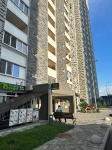 基辅Нова квартира з неймовірним краєвидом на озеро的坐在大楼前长凳上的男人