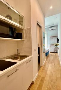 a kitchen with white cabinets and a sink and a hallway at Sea Glimpse Studio - Santa Lucia in Naples