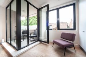 a room with glass doors with a chair and a table at Charming 1Bed Apt with Balcony - Steps from Tube in London