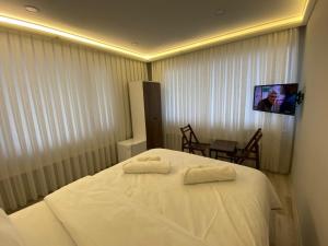 Habitación de hotel con cama blanca y TV en Yamaç Çam Hotel, en Trabzon