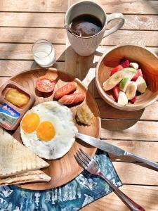 a plate of breakfast food with eggs and a bowl of fruit at Kacchapa Beach Resort and Restaurant in Sekongkang