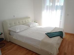 a bedroom with a white bed with a large window at City Apartment Dora in Makarska