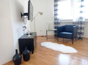 a living room with a blue chair and a rug at City Apartment Dora in Makarska